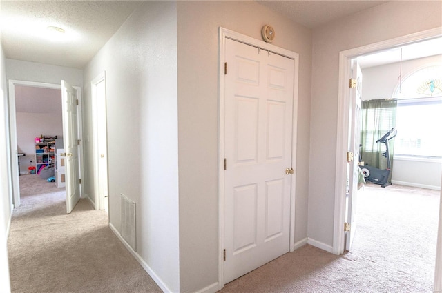 corridor featuring carpet, visible vents, and baseboards