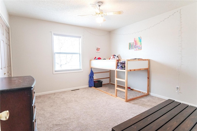 carpeted bedroom featuring a textured ceiling, a ceiling fan, and baseboards