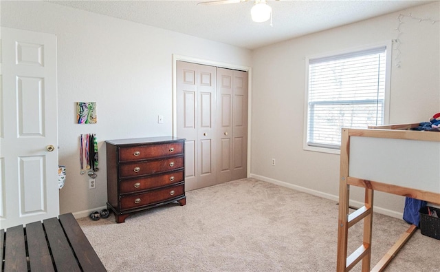 bedroom with light carpet, baseboards, ceiling fan, a textured ceiling, and a closet