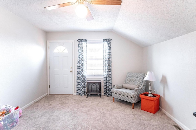 sitting room with a ceiling fan, carpet flooring, vaulted ceiling, a textured ceiling, and baseboards