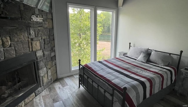 bedroom featuring a stone fireplace and hardwood / wood-style floors