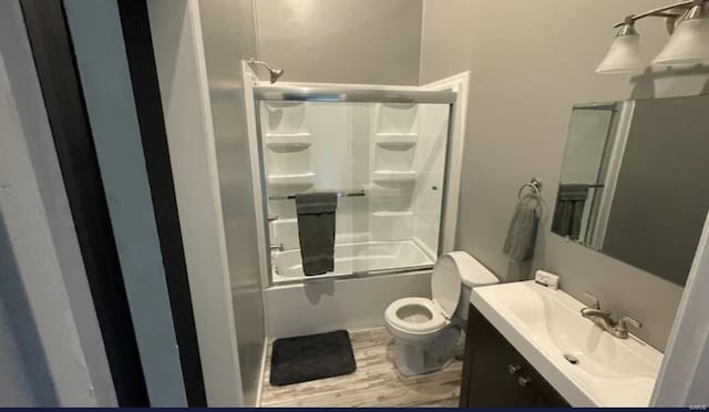 full bathroom with hardwood / wood-style flooring, vanity, toilet, and shower / bath combination with glass door