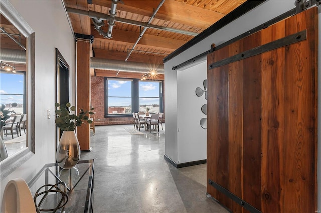 corridor featuring wooden ceiling, a barn door, concrete floors, beamed ceiling, and brick wall