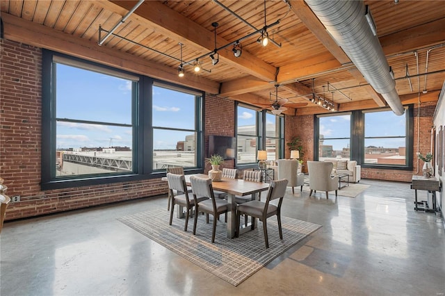 dining area with a healthy amount of sunlight, concrete flooring, and brick wall