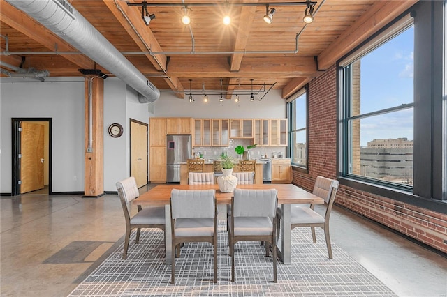 dining area with plenty of natural light, beam ceiling, wooden ceiling, and brick wall