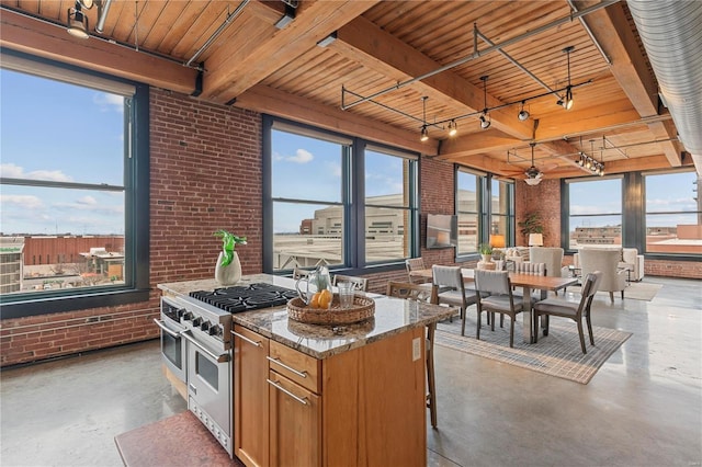 kitchen featuring light stone counters, brick wall, pendant lighting, double oven range, and a center island