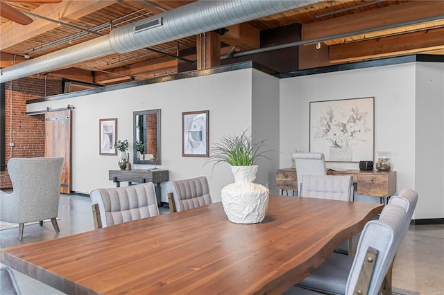 dining area featuring a barn door, concrete flooring, and a towering ceiling