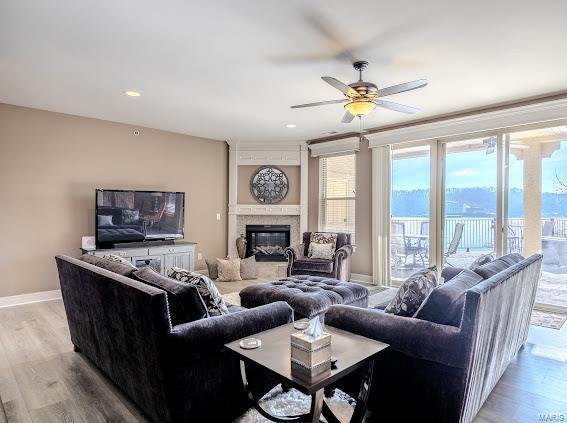 living room featuring ceiling fan, a high end fireplace, and light hardwood / wood-style floors