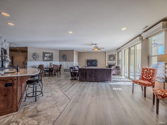 living room featuring light hardwood / wood-style flooring, ceiling fan, and sink