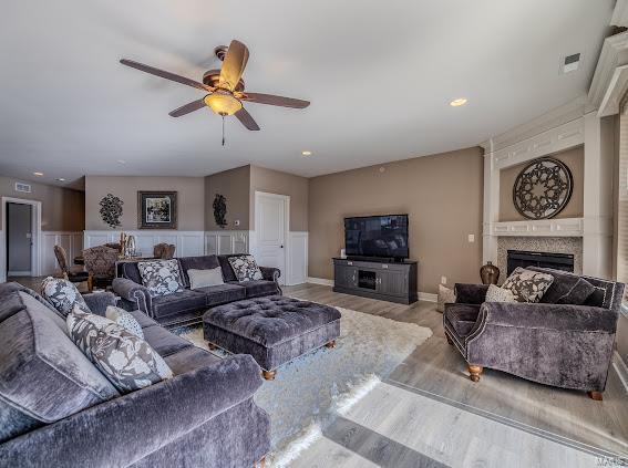 living room with a fireplace, light hardwood / wood-style floors, and ceiling fan