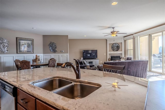 kitchen with light stone counters, stainless steel dishwasher, ceiling fan, sink, and hardwood / wood-style flooring