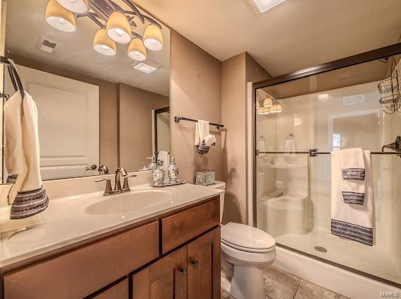 bathroom with tile patterned flooring, vanity, toilet, and an enclosed shower