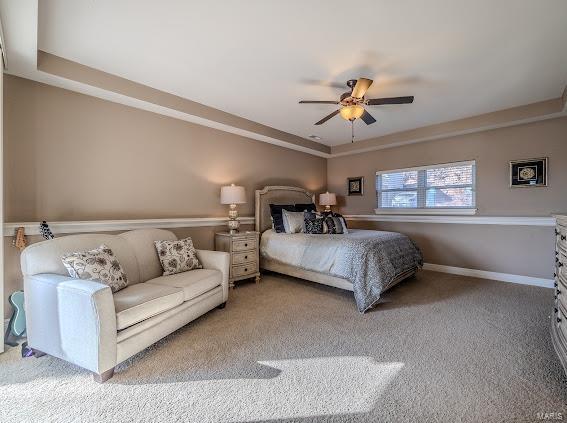 carpeted bedroom featuring ceiling fan and a tray ceiling