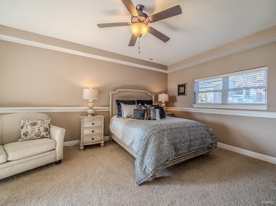 bedroom with a tray ceiling, ceiling fan, and carpet