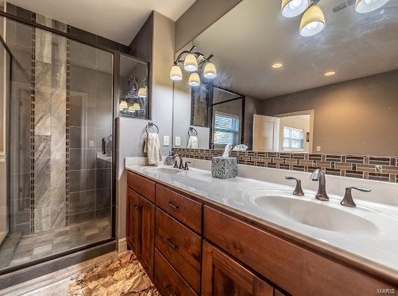 bathroom featuring vanity, tasteful backsplash, and a shower with door