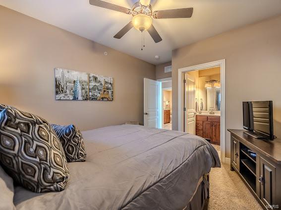 bedroom with ensuite bathroom, ceiling fan, and light carpet