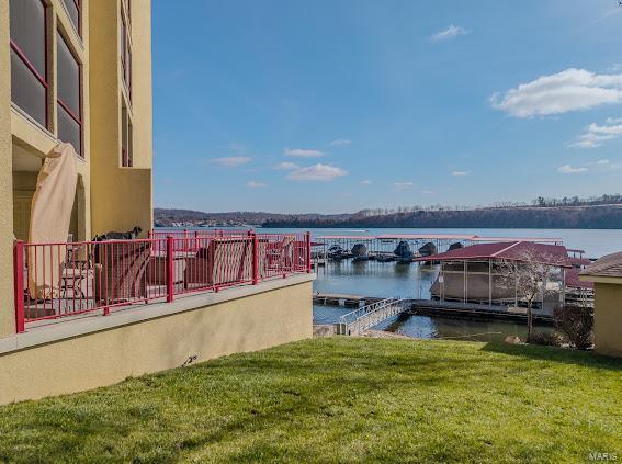 view of dock with a lawn and a water view