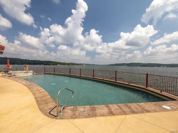 view of swimming pool featuring a water view and a patio