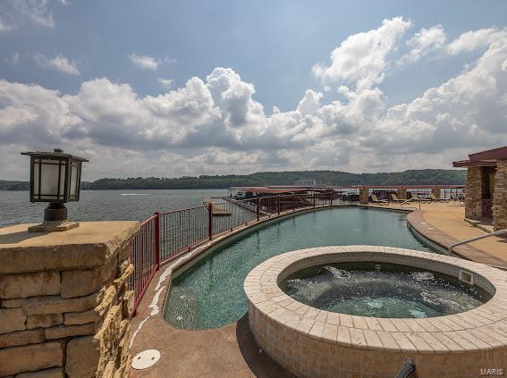 view of pool with a water view and an in ground hot tub