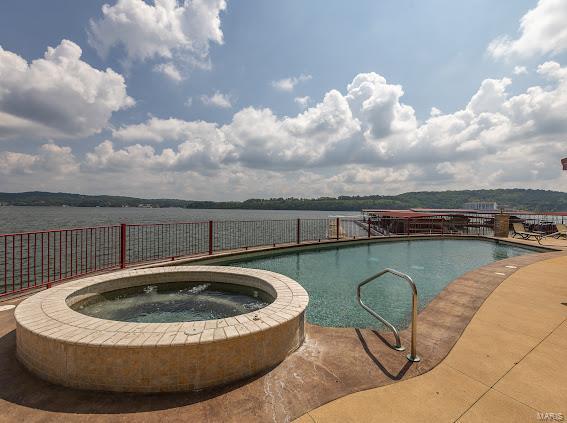 view of swimming pool with an in ground hot tub and a water view