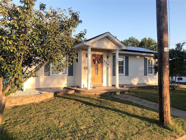 view of front of property with a front lawn and solar panels