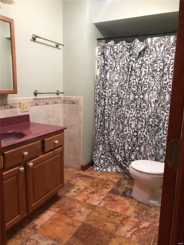 bathroom with vanity, toilet, and tile walls