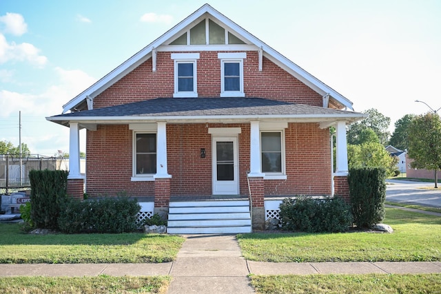 bungalow-style house featuring covered porch and a front yard