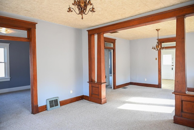 carpeted empty room with a chandelier and a textured ceiling