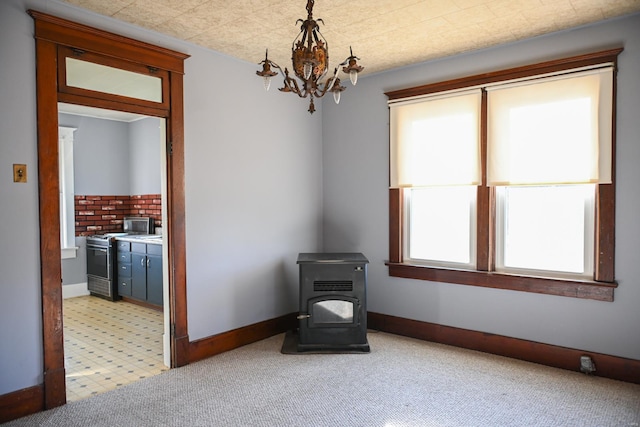 carpeted spare room with a chandelier and a wood stove