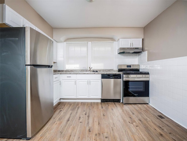 kitchen featuring light stone countertops, light hardwood / wood-style flooring, stainless steel appliances, white cabinets, and sink