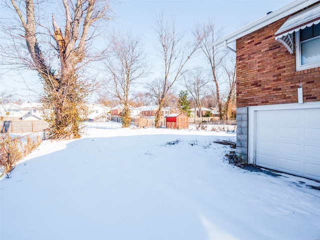 yard layered in snow featuring a garage and a shed