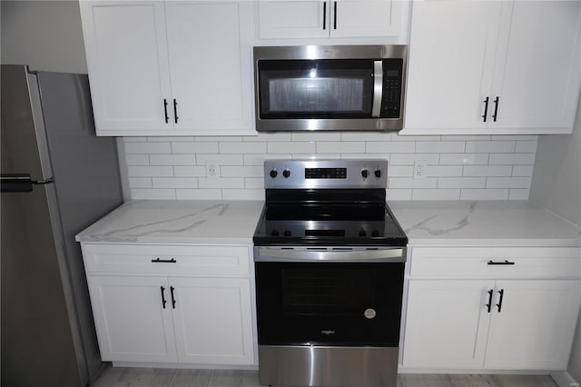 kitchen with decorative backsplash, stainless steel appliances, white cabinets, and light stone counters