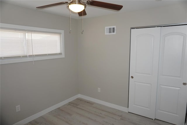 unfurnished bedroom with ceiling fan, light wood-type flooring, and a closet