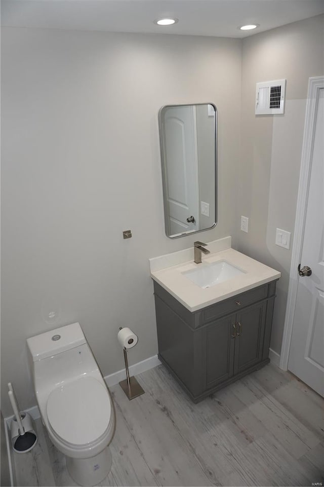 bathroom with hardwood / wood-style floors, vanity, and toilet