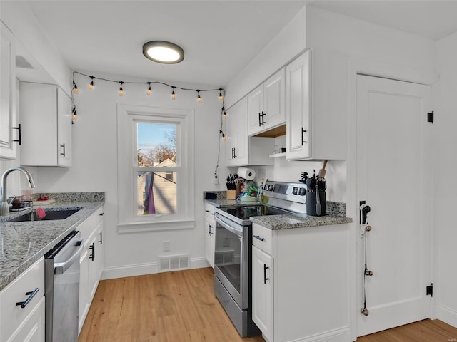 kitchen with sink, light hardwood / wood-style flooring, light stone counters, white cabinetry, and stainless steel appliances