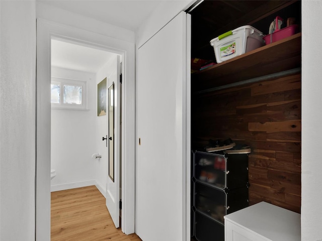 hall featuring light wood-type flooring and wooden walls