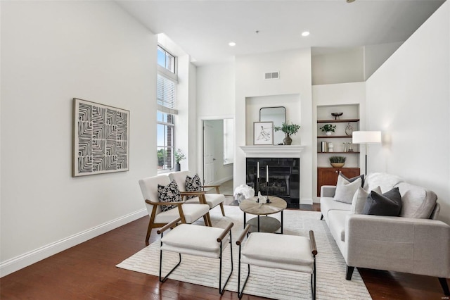 living room with built in shelves, dark hardwood / wood-style floors, and a high ceiling