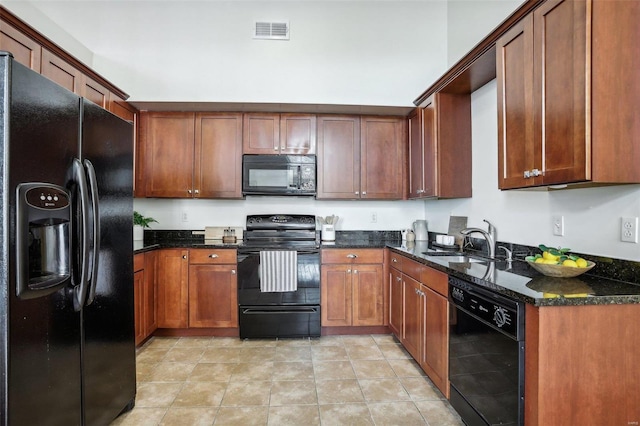 kitchen featuring light tile patterned floors, sink, dark stone counters, and black appliances