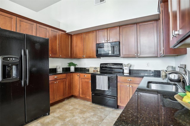 kitchen featuring dark stone counters, sink, light tile patterned floors, and black appliances