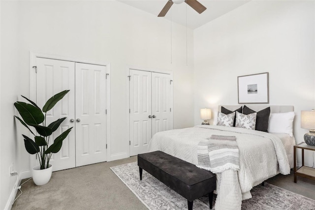 carpeted bedroom featuring multiple closets and ceiling fan