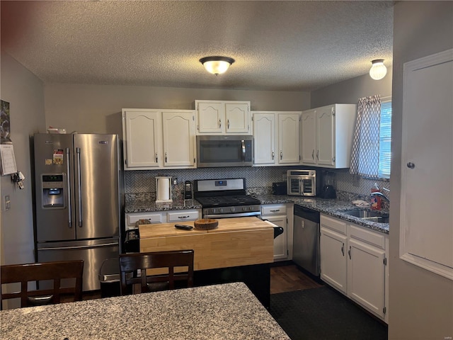 kitchen featuring white cabinets, sink, a textured ceiling, light stone counters, and stainless steel appliances