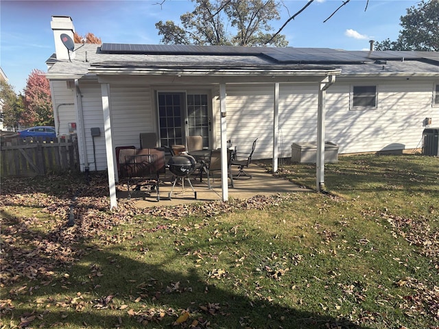 rear view of house with a lawn, a patio, and solar panels