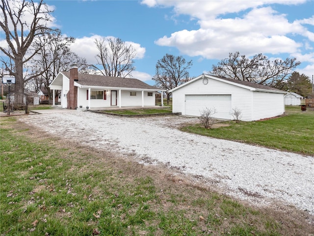 ranch-style home with covered porch, an outbuilding, a garage, and a front yard