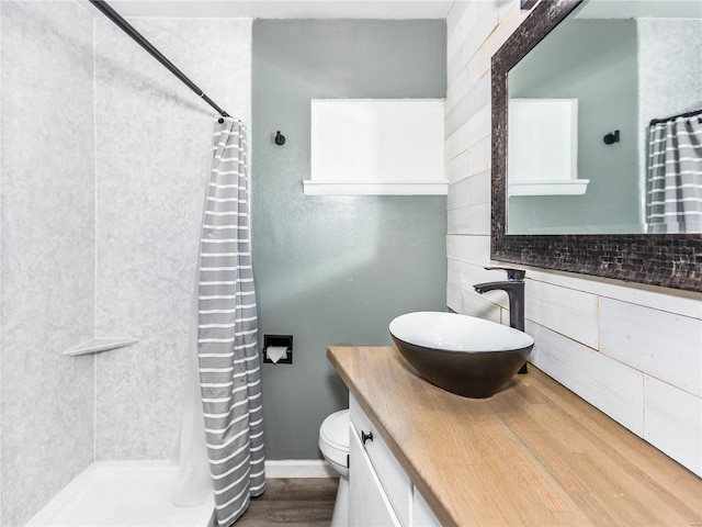 bathroom with hardwood / wood-style floors, vanity, toilet, and walk in shower