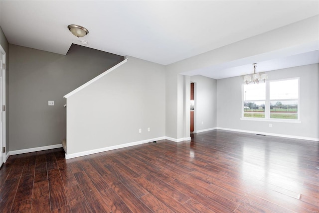 unfurnished living room with a notable chandelier and dark hardwood / wood-style floors