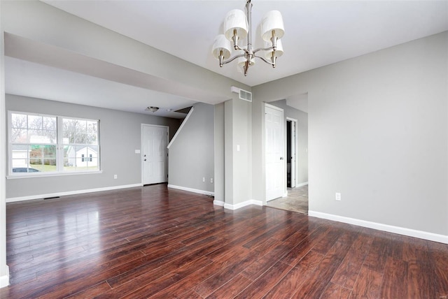 unfurnished living room featuring dark wood-type flooring and a notable chandelier