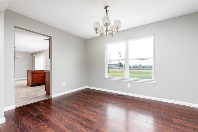 empty room with hardwood / wood-style floors and a chandelier