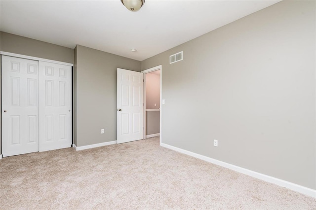 unfurnished bedroom featuring light carpet and a closet