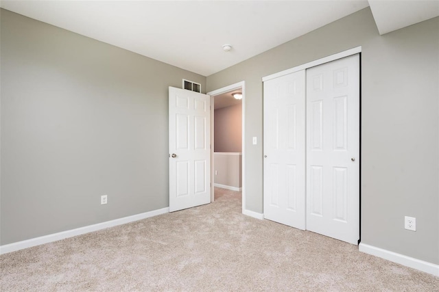 unfurnished bedroom featuring light carpet and a closet