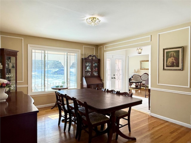 dining area featuring an inviting chandelier, light hardwood / wood-style floors, and french doors